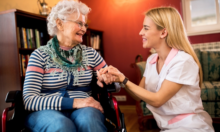 Family member leans in lovingly to talk with a senior; daughter or grand-daughter talks with mom, grandmother, great aunt about senior care.