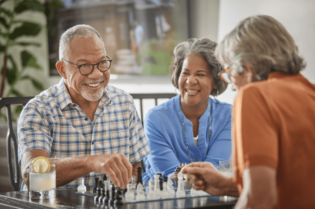 Three elderly people playing a game of chess